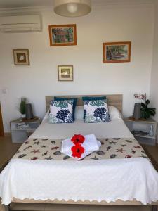 ein Schlafzimmer mit einem Bett mit einer roten Blume darauf in der Unterkunft Le PARADIS DE LA COTE SUD EST ALGARVIA in Altura