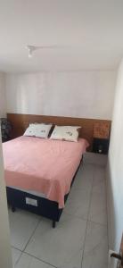 a bedroom with a bed with a pink blanket and two pillows at Impérium residence clube in João Pessoa
