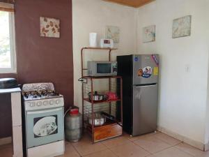 a kitchen with a refrigerator and a microwave and a stove at Casa con Piscina privada Wifi TV Cocina Completa Cerca de Playa La Ermita in San Carlos