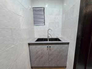 a kitchen with a sink in a white tiled wall at Twinny properties in Lagos