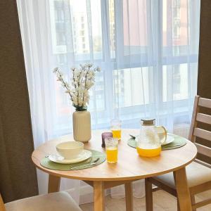 einen Tisch mit einer Vase Blumen und zwei Gläsern Orangensaft in der Unterkunft ЦЕНТР ГОРОДА & PERFECT APARTMENT & CENTER OF THE CiTY in Almaty