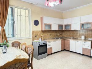 a kitchen with white cabinets and a table and a dining room at Yoga Guesthouse in Shkodër