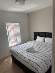 een slaapkamer met een bed met een zwart hoofdeinde en een raam bij Two bedroom house free parking in Liverpool