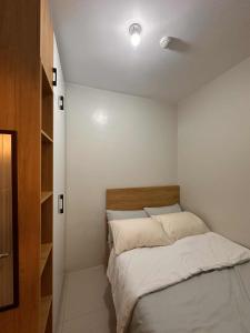 una piccola camera da letto con un letto con lenzuola bianche di Eu & El Cozy Condo a Manila