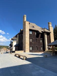 a large brick building with a bench in front of it at Jaram Vile Apartmani in Kopaonik