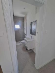 a white bathroom with a sink and a toilet at Karyatis Building in Nicosia