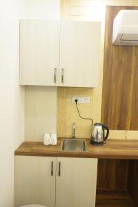 Una cocina con fregadero y gabinetes blancos. en Hillshades Comfy rooms, en Dagshai 17 fotos más