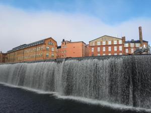 a waterfall on the side of a river with buildings at Stor lägenhet för familj eller företag in Norrköping
