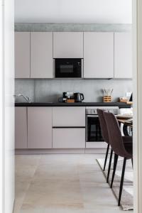 a kitchen with white cabinets and a table with chairs at A26 Condo by the Rhine and 3-countries-bridge in Huningue
