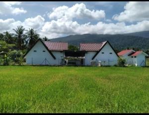 a couple of white buildings in a field of grass at Nekmah Chalet in Yan