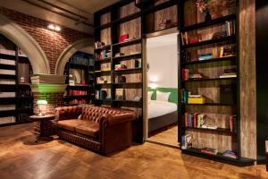 a library with a brown leather chair and books at Hotel Not Hotel Amsterdam in Amsterdam