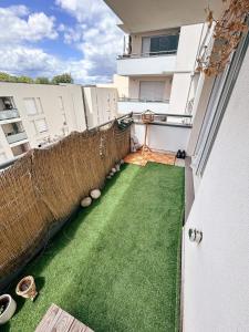 a balcony with a green lawn on a building at Grand T2 lumineux, 74 m in Villefranche-sur-Saône +2 photos