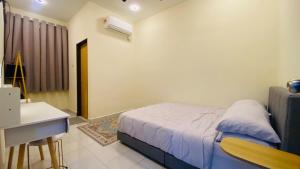 a bedroom with a bed and a desk and a table at Prima Lodge Homestay in Kulim