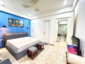 una camera con letto, TV e pareti blu di The Olivia 5 Star 1BHK Luxury suite a Rishikesh