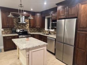 a kitchen with wooden cabinets and stainless steel appliances at Poolside Retreat with Private Patio in Brampton