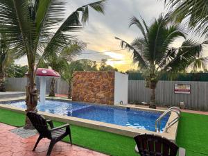 a swimming pool in a yard with two chairs at Rumah Kebun Gucher in Kuala Terengganu