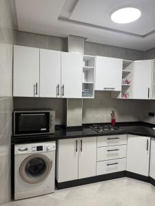 a kitchen with white cabinets and a washing machine at Martil appartement avec vue sur mer in Martil