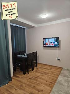 Un comedor con una mesa y un televisor en la pared. en Apartments Vilma&Villiam, en Ravda