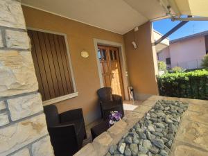 a house with two chairs and a stone wall at La casa di Amelie in Flero