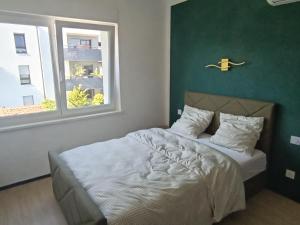 a bedroom with a bed with a green wall and a window at NG-Global Home in Sierentz