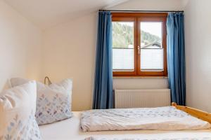a bedroom with a bed with blue curtains and a window at Ferienwohnung Alpenpanorama in Oberau