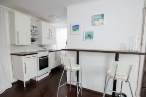 a kitchen with white cabinets and white bar stools at White House Balatonberény in Balatonberény