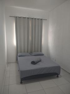 a bed in a white room with a curtain at Casa com 03 Quartos, Piscina e Churrasqueira em Itaipuaçu Maricá RJ in Maricá