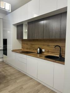 a kitchen with white cabinets and a sink at ЖК Green Plaza Aktau Двухкомнатная большая in Aktau +3 photos