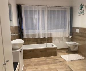 a bathroom with a tub and a toilet and a sink at Smaragdherz in Bramberg am Wildkogel