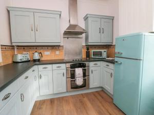 eine Küche mit weißen Schränken und einem blauen Kühlschrank in der Unterkunft Cosy Cottage in Cumbria, West of Lake District in Broughton Moor + 52 Fotos