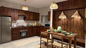 a kitchen with wooden cabinets and a wooden table with chairs at Cozy 2BRs chalet in Einbay Boho designed in Ain Sokhna