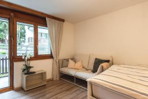 una camera da letto con un letto, un divano e una finestra di Zermatt - well located and equipped studio a Zermatt