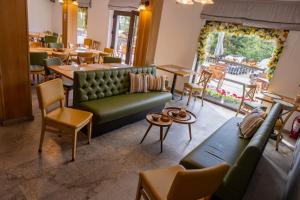 a restaurant with a green couch and tables and chairs at Pensiune Rara Paltinis in Păltiniş