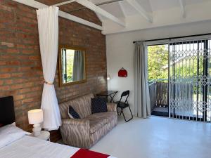 a bedroom with a bed and a couch and a window at Quilla Quarters in Plumstead