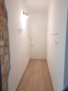 een hal met een witte deur en een houten vloer bij Domus 1 in Negrar