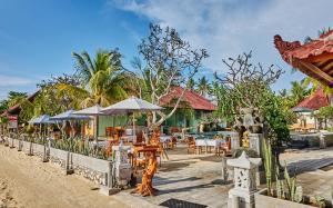 a restaurant with tables and umbrellas on a beach at Scoobydoo Bungalow in Nusa Lembongan