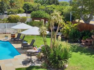 Eine Person liegt auf einer Rasenfläche neben einem Pool in der Unterkunft Suite Shiraz in Meadowridge