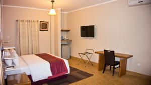 a hotel room with a bed and a desk with a computer at Tropical Enclave Hotel in Accra