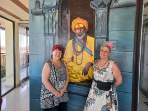 three women standing in front of a painting of a man at KS PAYING GUEST HOUSE in Varanasi
