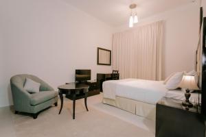 a bedroom with a bed and a desk and a chair at Alraya Homes by Betu former Times Inn in Abu Dhabi +59 photos