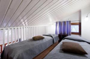 two beds in a bedroom with a wooden ceiling at Raito Apartment in Saariselka