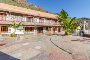 a building with a courtyard with palm trees in front of it at Los Penones Experiences A - Solo Adultos in El Sao