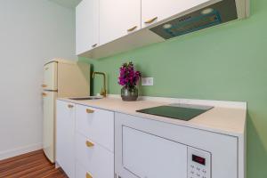 a kitchen with white cabinets and a refrigerator at Los Penones Experience B - Solo Adultos in El Sao