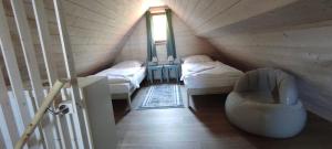 Una habitación abuhardillada con dos camas y una silla. en Pod farárovou hôrkou, en Banská Štiavnica