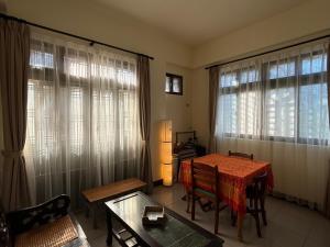 a living room with a table and chairs and windows at Jiufen Gourd Stone TreeHouse 137 in Ruifang