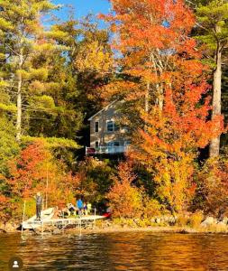 una casa en la orilla de un lago con hojas de otoño en The Lookout at Loon Lake, en Plymouth