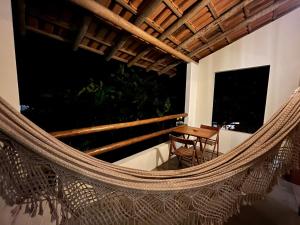 a hammock on the balcony of a house with a table at Suítes Aracuã in Caraíva