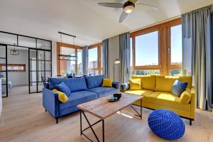 a living room with blue and yellow couches and a table at Staywin Aura Gdańsk I in Gdańsk