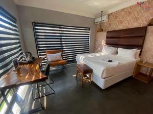 a bedroom with a white bed and a table and a chair at ANISA GUESTHOUSE in Thohoyandou