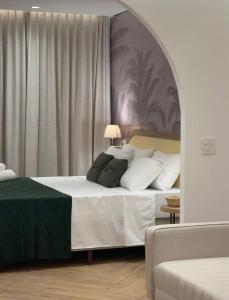 a bedroom with a bed with white sheets and green pillows at Santé Vivre L'Experience in Búzios